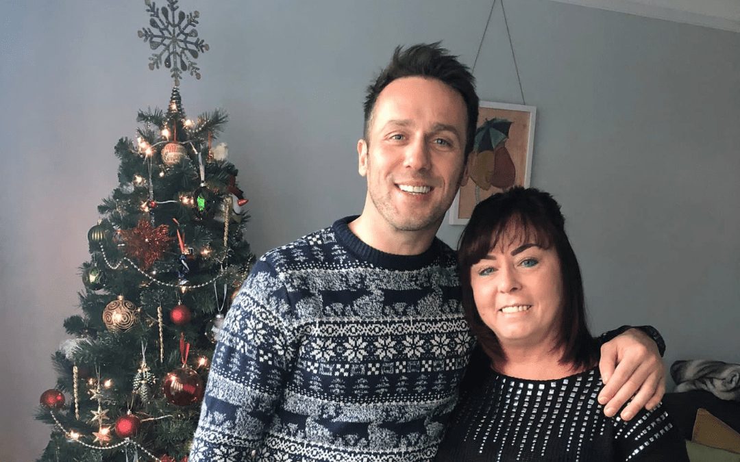 2 people stood in front of a christmas tree